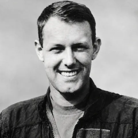 Black-and-white portrait of Steve Hanson, smiling, in a flight jacket.
